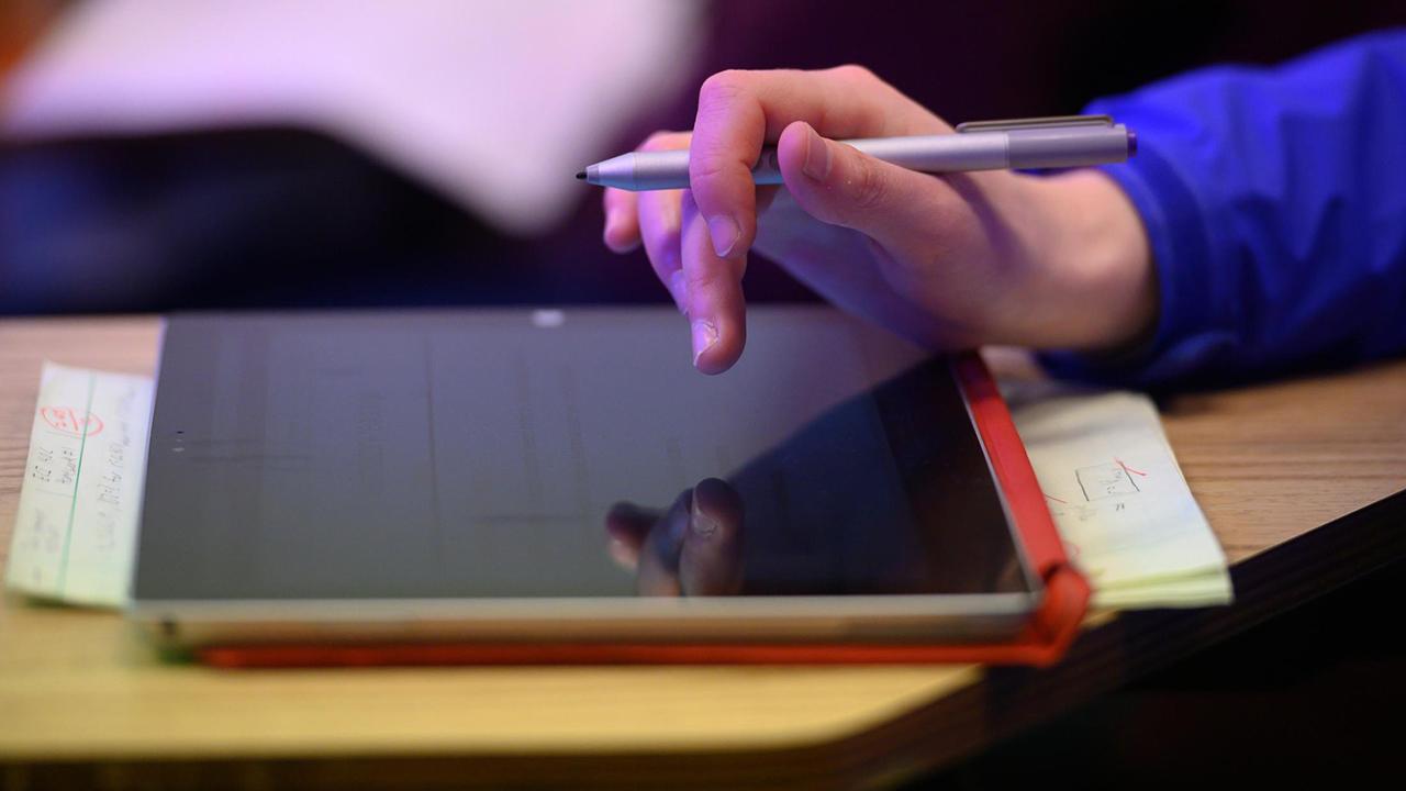 closeup of student touching tablet screen