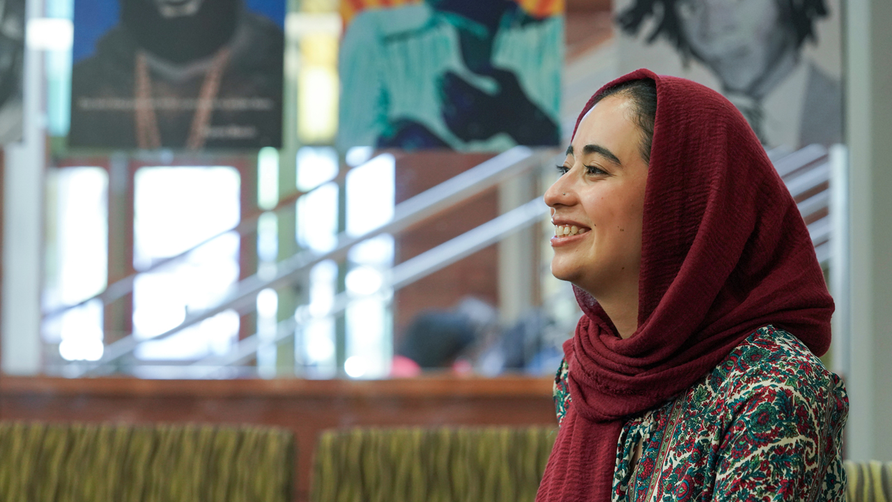 UC Davis student in headscarf smiles while sitting on campus