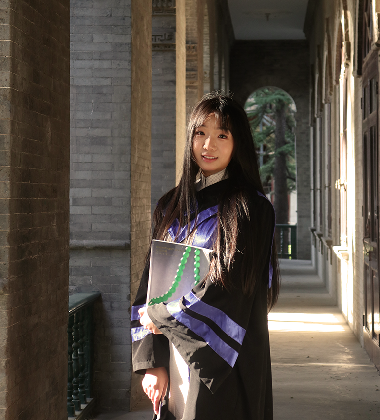 YiFei poses in her graduation cap after earning her Master’s degree in arts from Renmin University of China