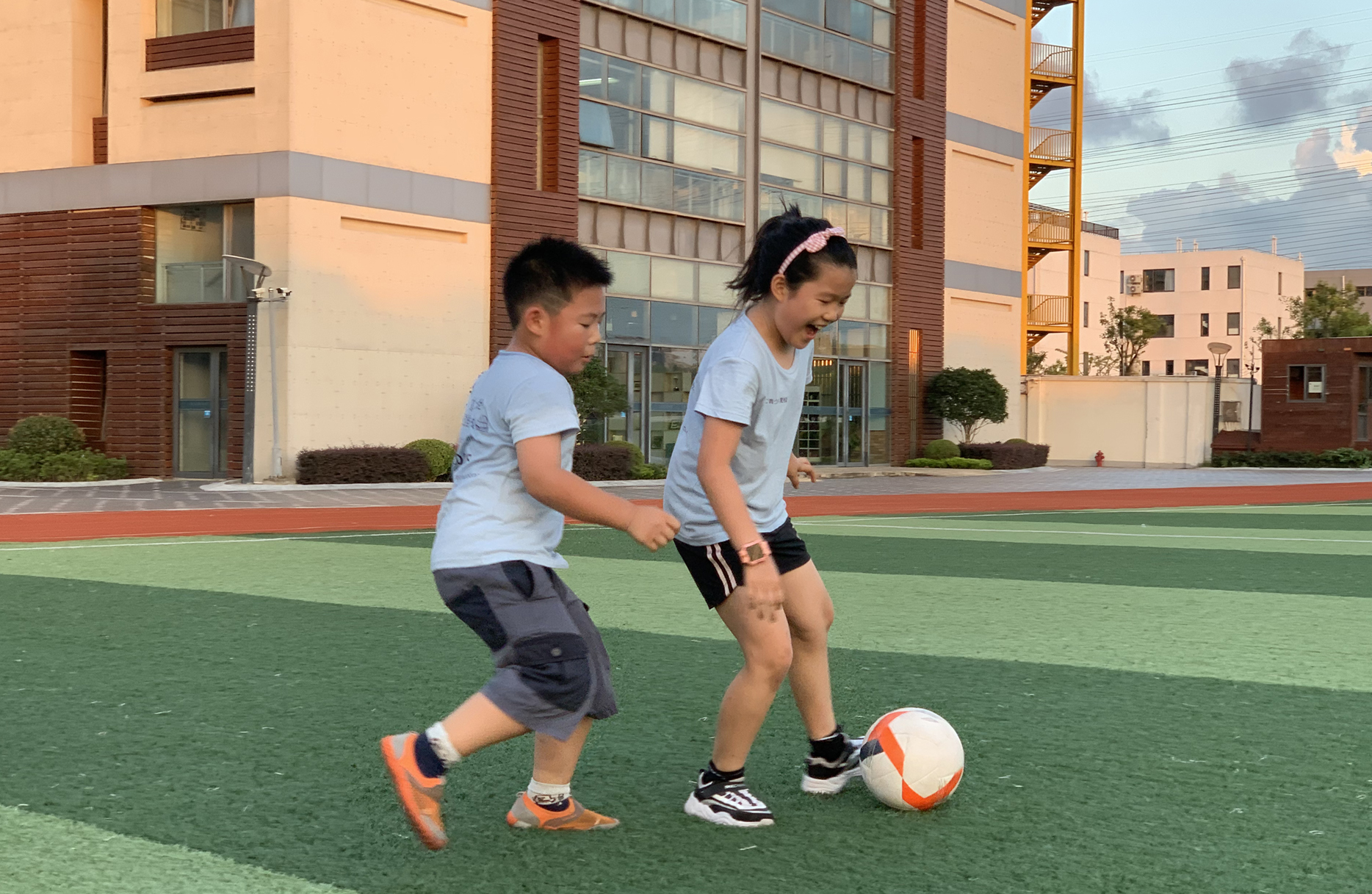 two kids play soccer on a field