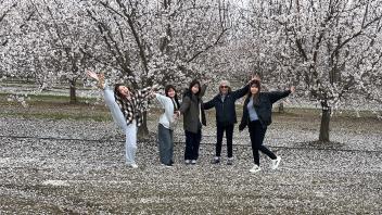 A group of International students poses under almond flowers