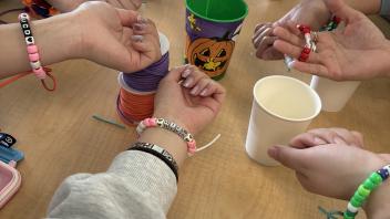 Students show off the bracelets they made on their wrists