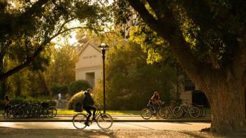 A student rides her bike past a bike rack by George Hart Hall