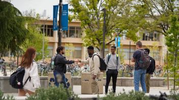 Students talking on the pathway near Walker Hall and Shields Library.