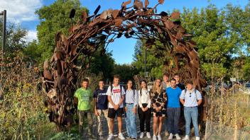 students stand in front of a metal archway at the UC Davis Arboretum