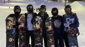 group of students pose at Lake Tahoe in snow gear holding their snowboards
