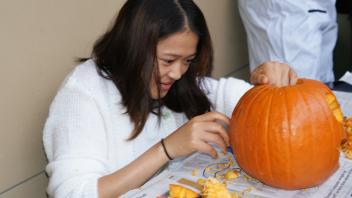 UC Davis international student carve pumpkins at a Halloween party