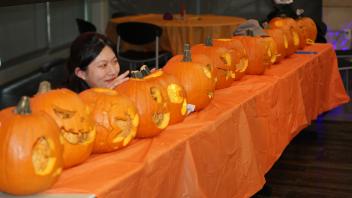A UC Davis international student poses with a row of carved pumpkins