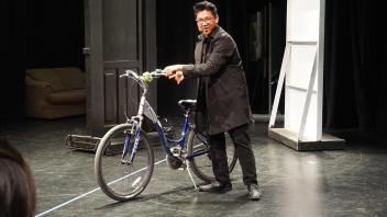 a student performs on stage alone with a bike used as a prop