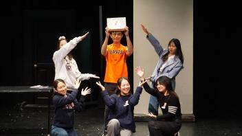 a group of students stand and kneel on stage together as they perform