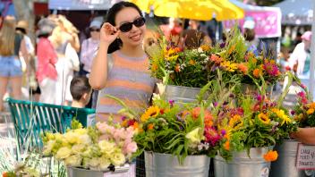 Yile Miao enjoys the vibrant flower selection at the Davis Farmers Market.