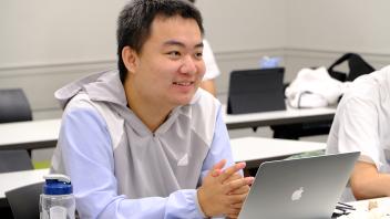 GREAT Program at his desk with laptop asks a thoughtful question of UC Davis Prof. during a lecture