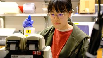 Ruoyu Li, a biology major from the GREAT 2024 Program, carefully operates the lab equipment in front of a centrifuge in Prof. Lifeng Xu's Lab