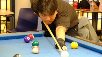 A student focuses during a game of billiards in the MU Game Area