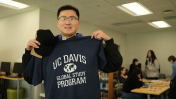 a new Global Study Program student holds up his GSP shirt during orientation