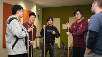 students and staff prepare for a friendly game of billiards