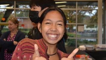 an international student poses with two thumbs up during the Thanksgiving celebration