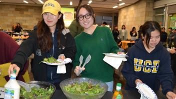 international students pose for a photo while grabbing food from the Thanksgiving buffet line
