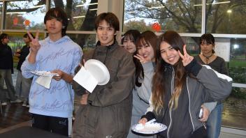 international students pose for a photo while waiting in line to grab a plate of Thanksgiving food