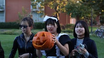 UC Davis international students pose in costume with their carved pumpkins 