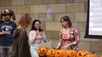 Students view pumpkins lined up on a table for the pumpkin carving competition