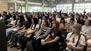 a large group of UC Davis international students sit in the International Center during orientation