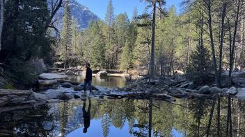 International Business student at UC Davis Carlos Maya Ortega walks across a stream at Yosemite