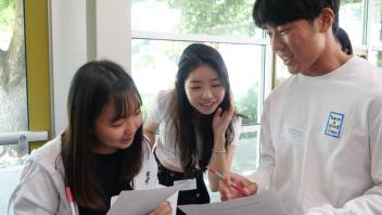 Three Global Study Program students engage in a worksheet activity during their orientation