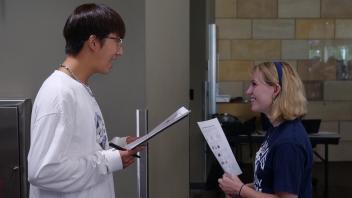 Two Global Study Program students face each other and talk while engaging in an activity during orientation