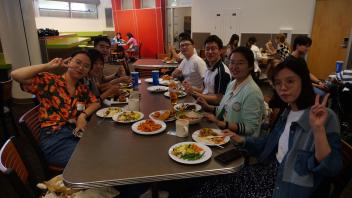 Global Study Program students sitting at a table eating, stop to pose for the camera