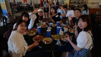 Global Study Program students sitting at a table eating, stop to pose for the camera