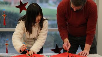 GSP student Shuyi Li teaches staff member Alex Hovan how to do Chinese calligraphy