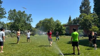 UC Davis international students play volleyball on the lawn with sprinkles on