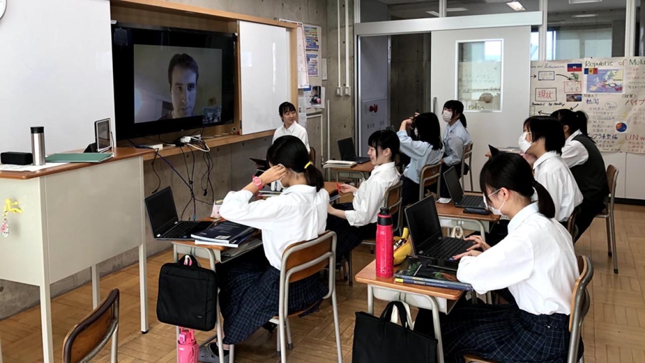 high school students in classroom listen to a lecture on an overhead screen