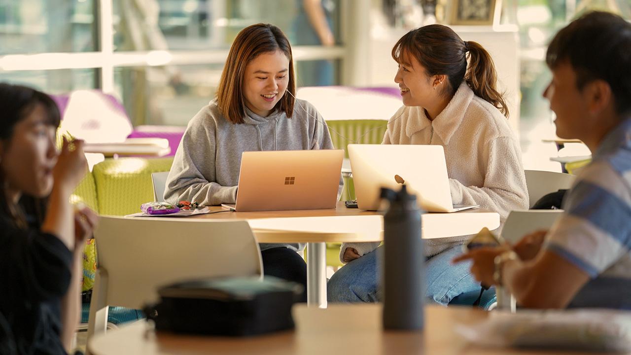 students sit at a desk talking and working on their laptop at the UC Davis international center