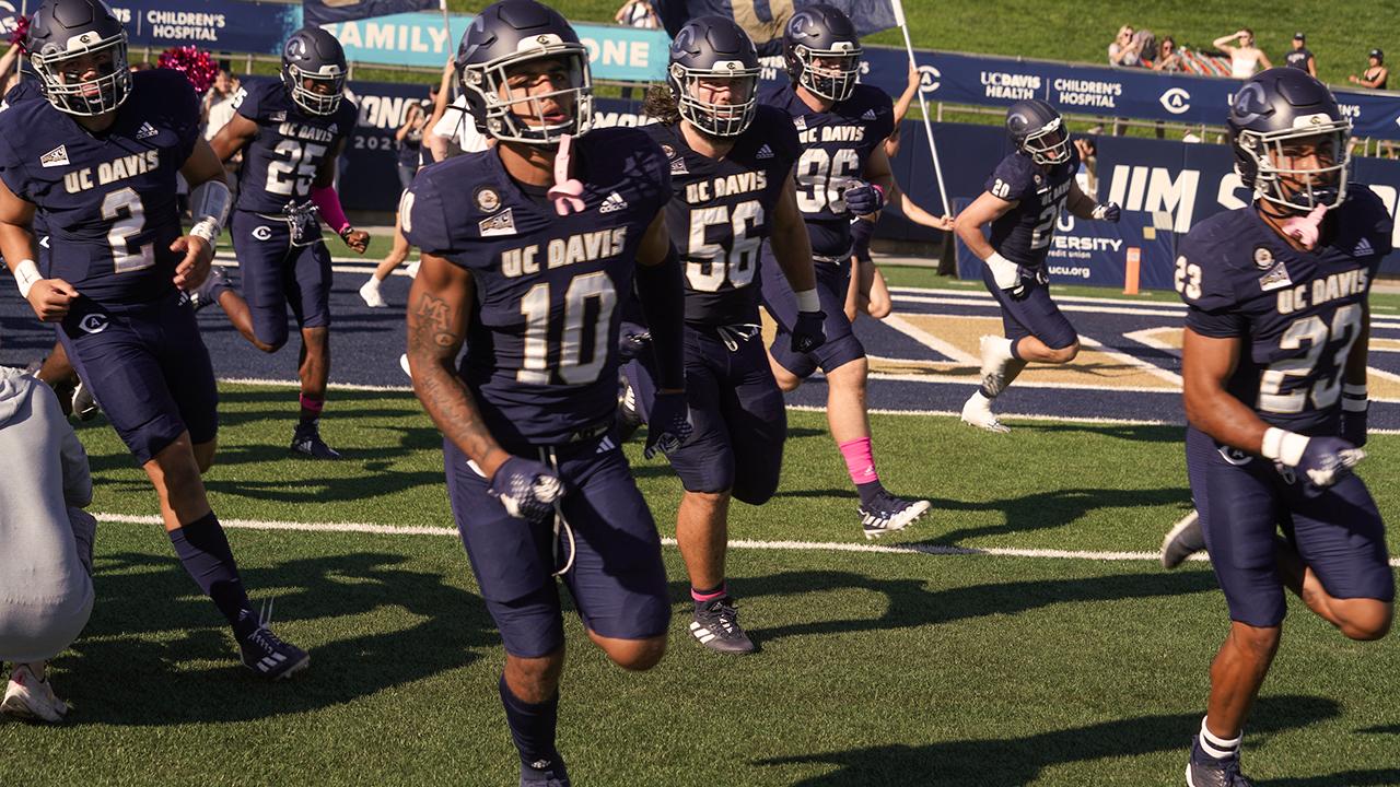 UC Davis football players run out onto the field during a homecoming game