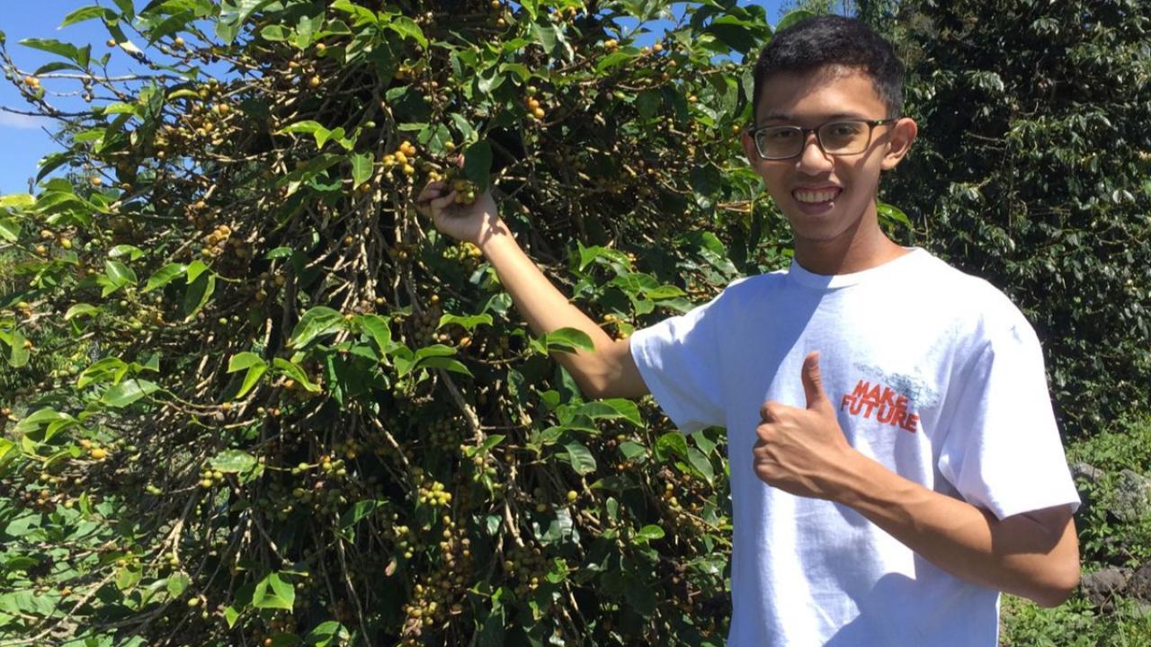 Student Bimo Abdusshamad next to coffee tree in Indonesia