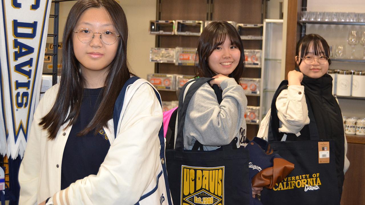international youth students pose in the UC Davis bookstore with UC Davis gear