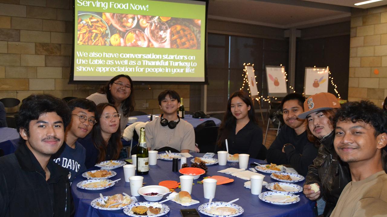 a group of international students pose at a table during their Thanksgiving celebration