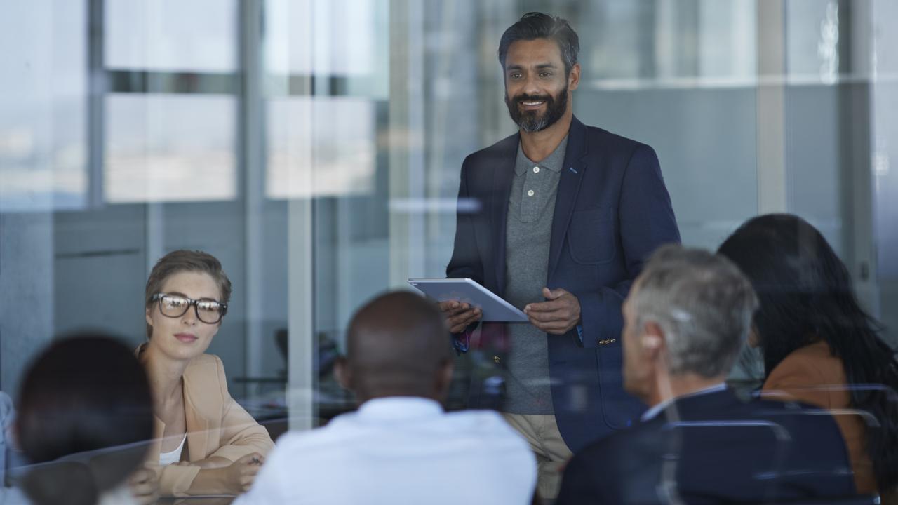 Business people talking together in large glass conference room