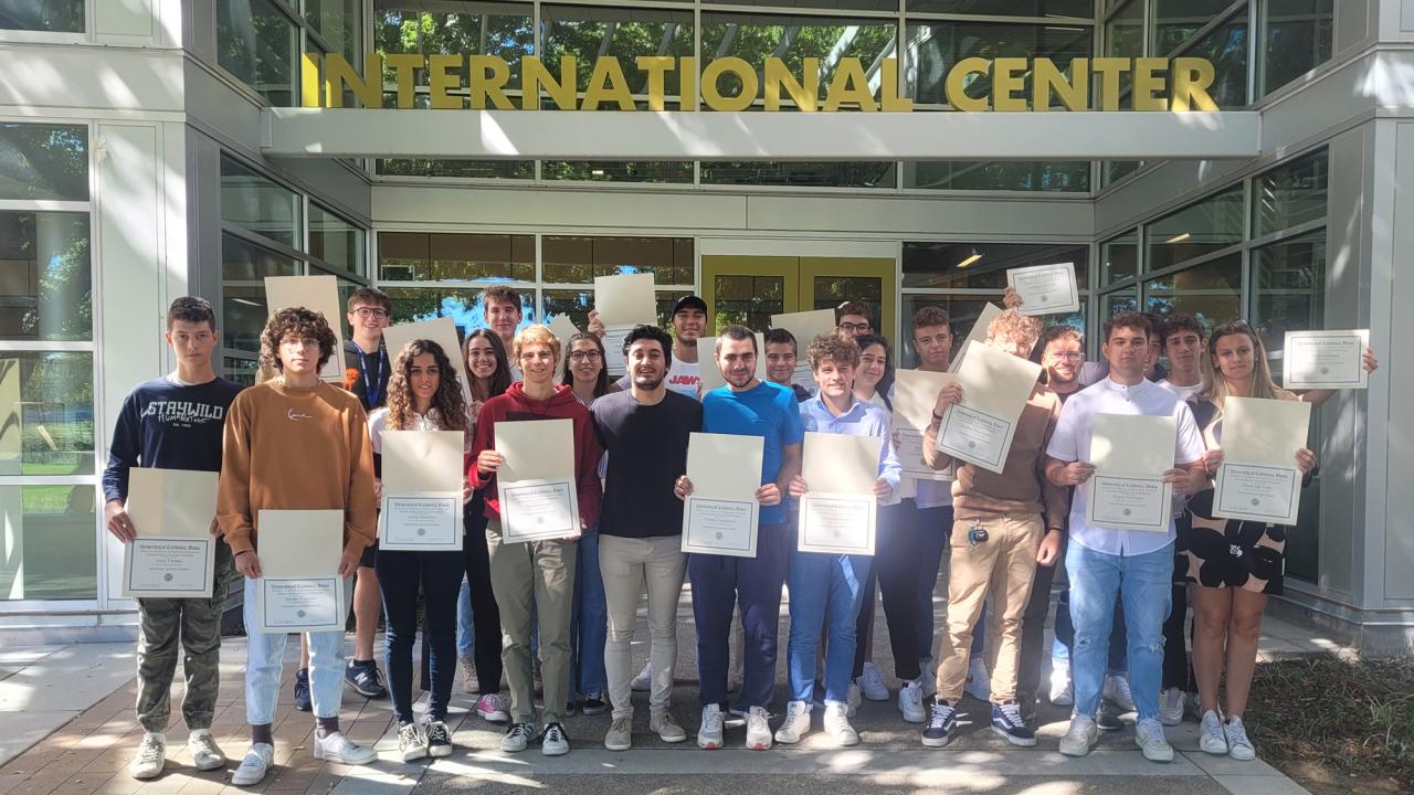 group of high school students stand outside UC Davis International Center holding their certificates