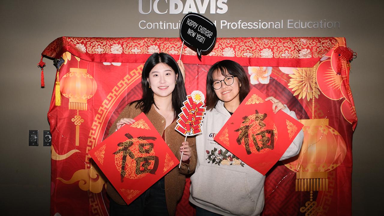 Two GSP students pose with Chinese calligraphy during the Lunar New Year celebration at the International Center UC Davis.