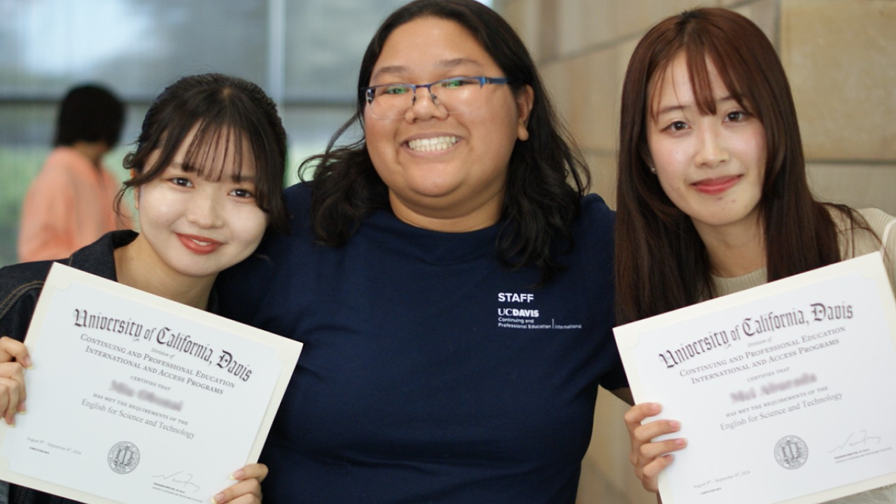 UC Davis student assistant Nicole Purba poses with two international students as they hold up their certificates