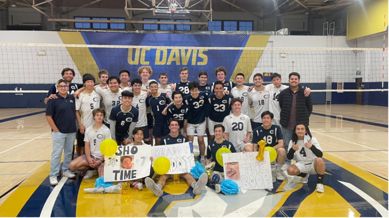 group of students on UC Davis volleyball court holding signs up
