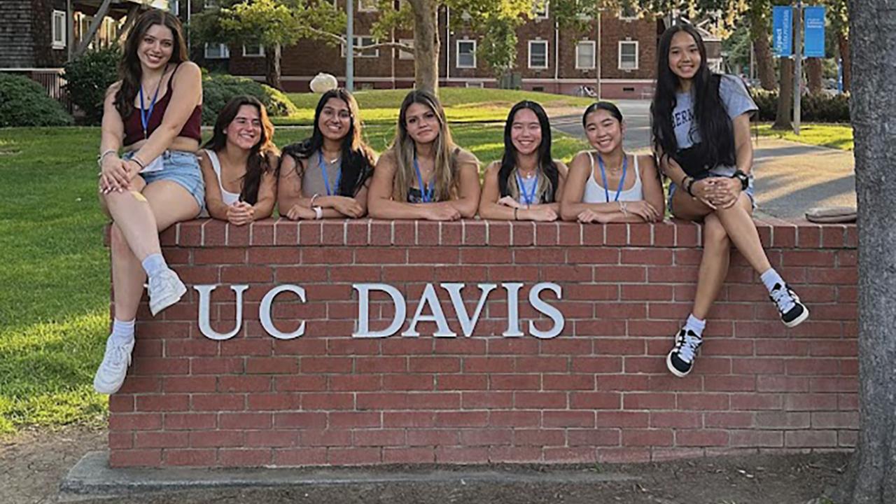 UC Davis pre-college students pose on the UC Davis sign