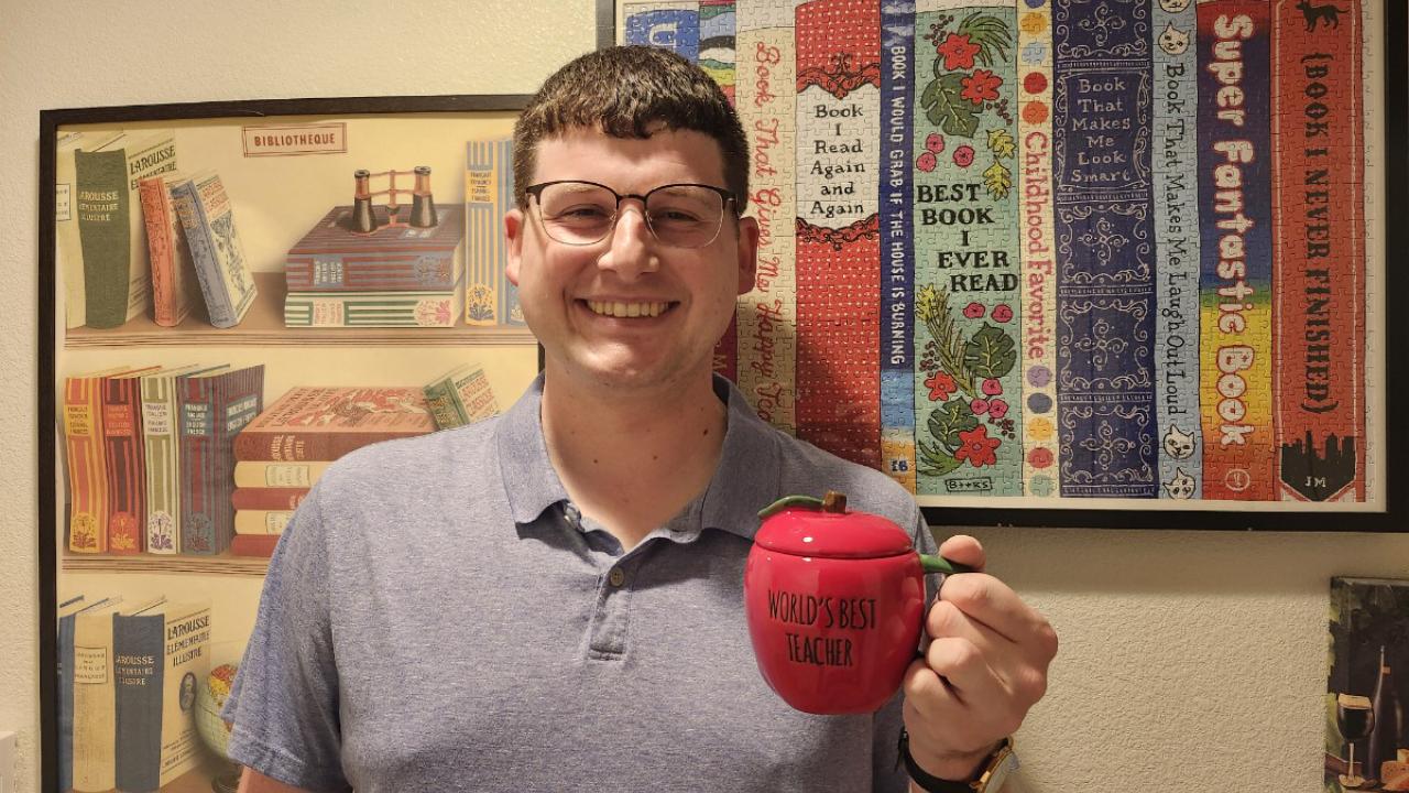headshot of UC Davis International programs instructor Thomas Hardy posing with "World's bet teacher" mug