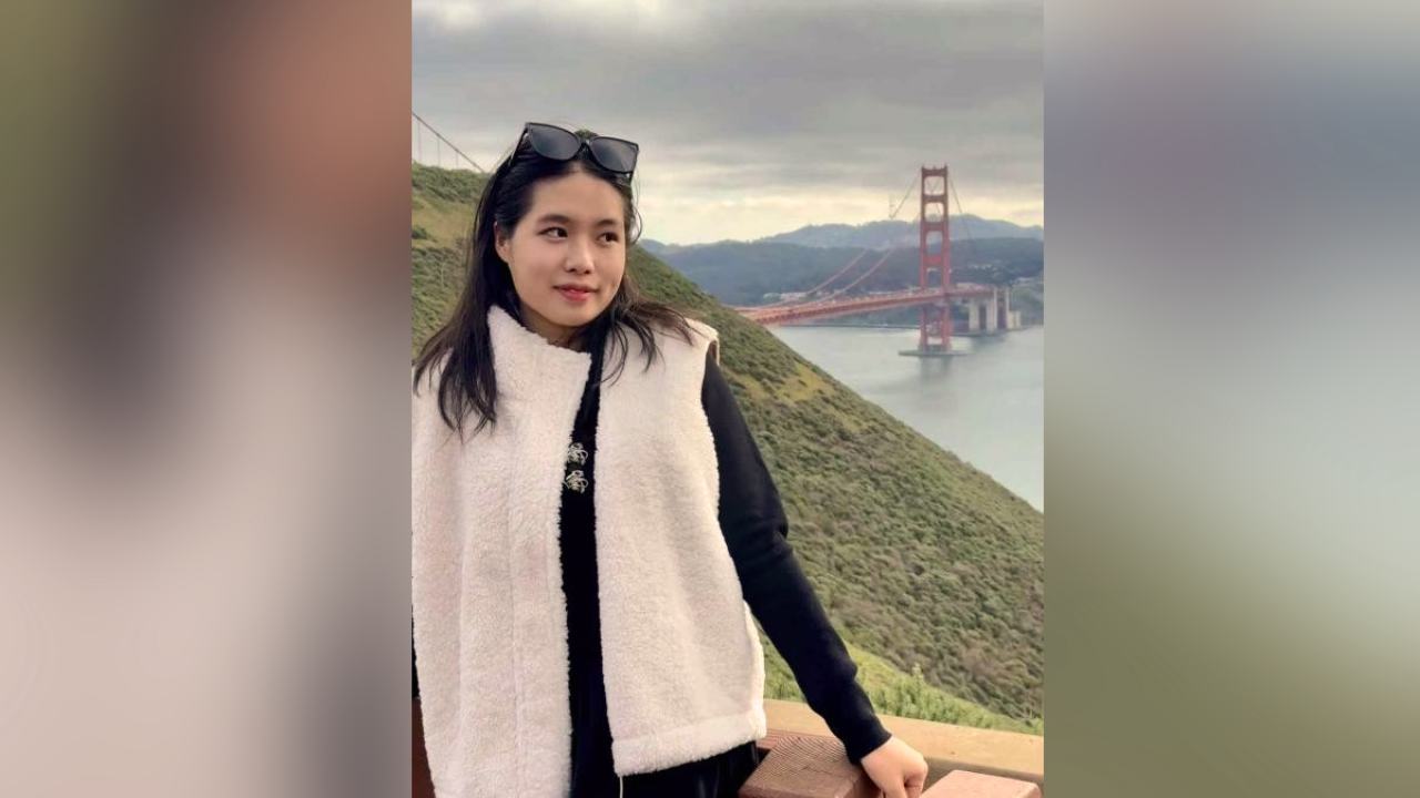 Woman photographed at Golden Gate Bridge overlook, wearing white sherpa vest, overcast sky