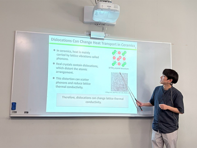 A student pointing at presentation slide on whiteboard in classroom