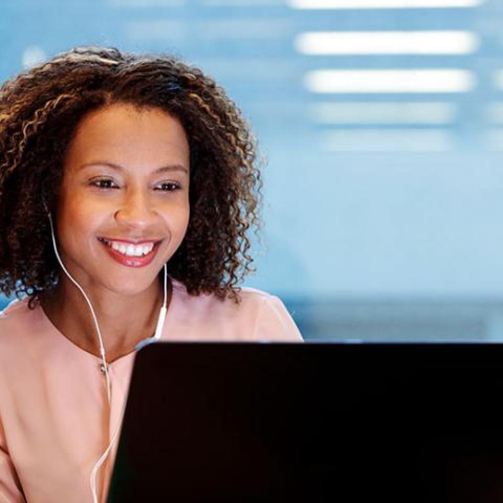 woman sits at laptop smiling
