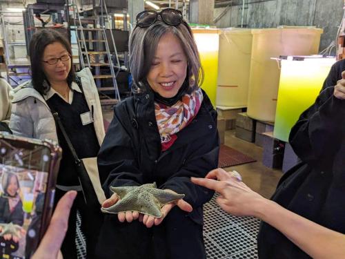 A delegation member holds a sea star in the wet lab at UC Davis Bodega Marine Laboratory.